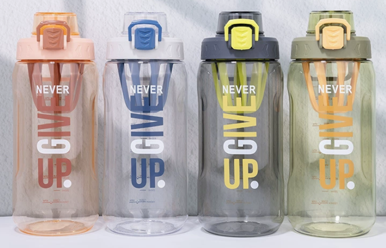 A close-up of a hand carefully applying a custom-cut white vinyl name decal to a clear plastic water bottle.