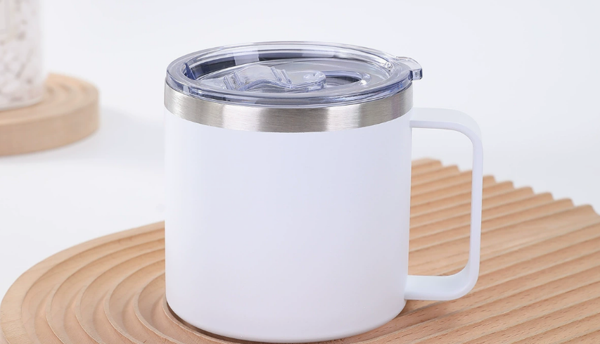 A stylish sublimation coffee mug with a secure lid sitting on a desk, with a person happily sipping from it.